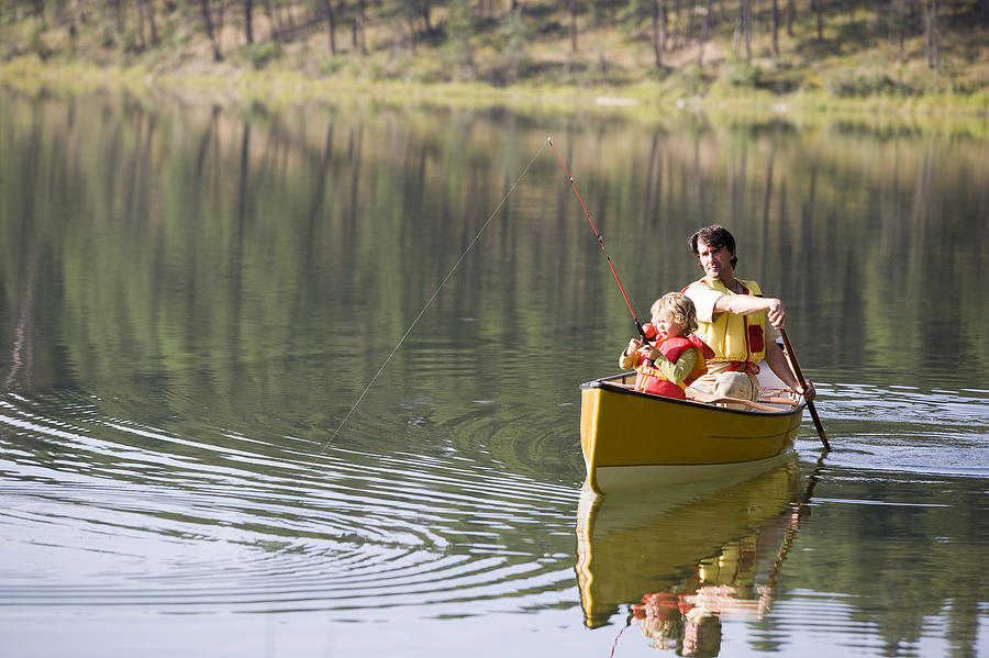 Father and daughter fishing from canoe Photograph by Comstock Images