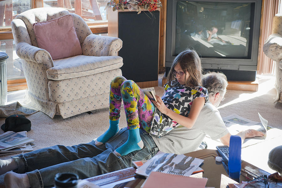 Father and daughter reading on living room floor Photograph by Stephen Simpson