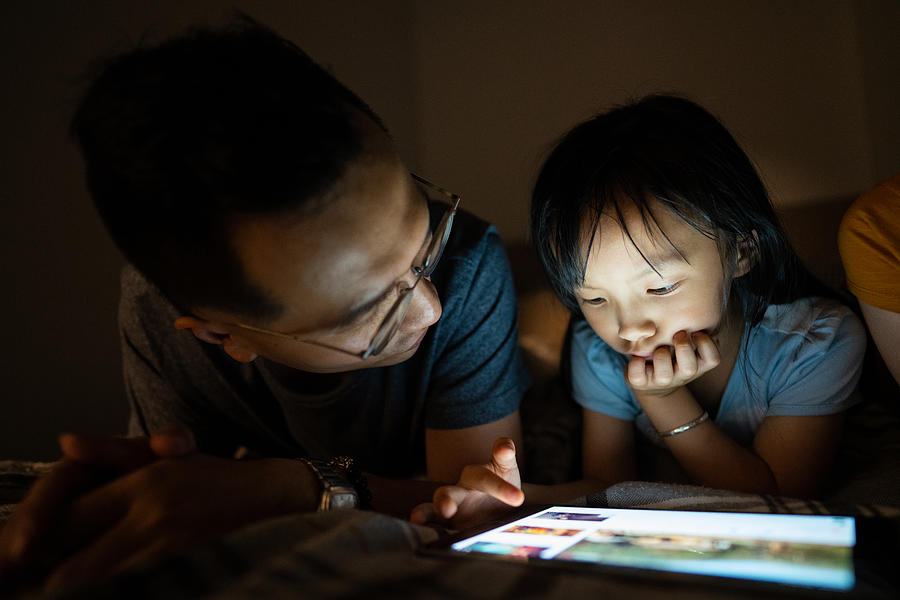 Father and daughter using tablet before sleeping Photograph by Miodrag Ignjatovic