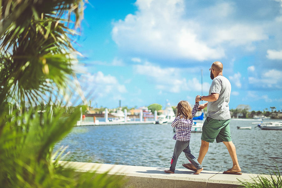 Father and daughter walk along the waterfront in sunny tropical location Photograph by Lisa5201