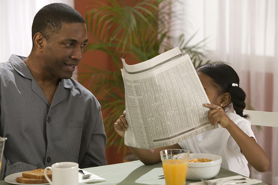 Father and daughter with newspaper Photograph by Comstock Images