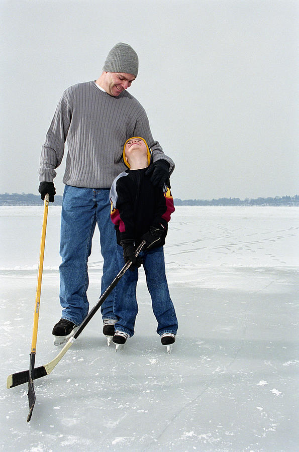 Father and son (4-6) playing ice hockey on frozen lake Photograph by Jim Arbogast