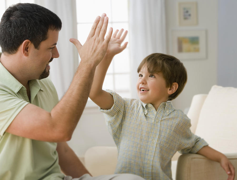 Father and son (6-7) making high five, smiling Photograph by Jose Luis Pelaez