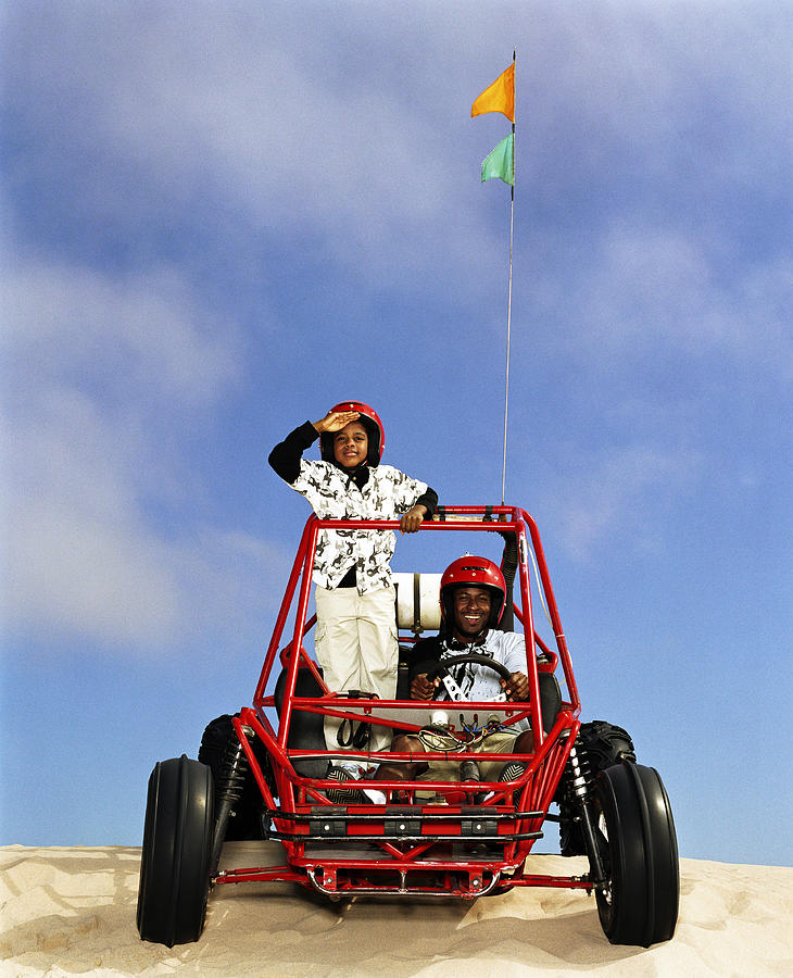 Father and son (8-10) riding in dune buggy Photograph by LifesizeImages