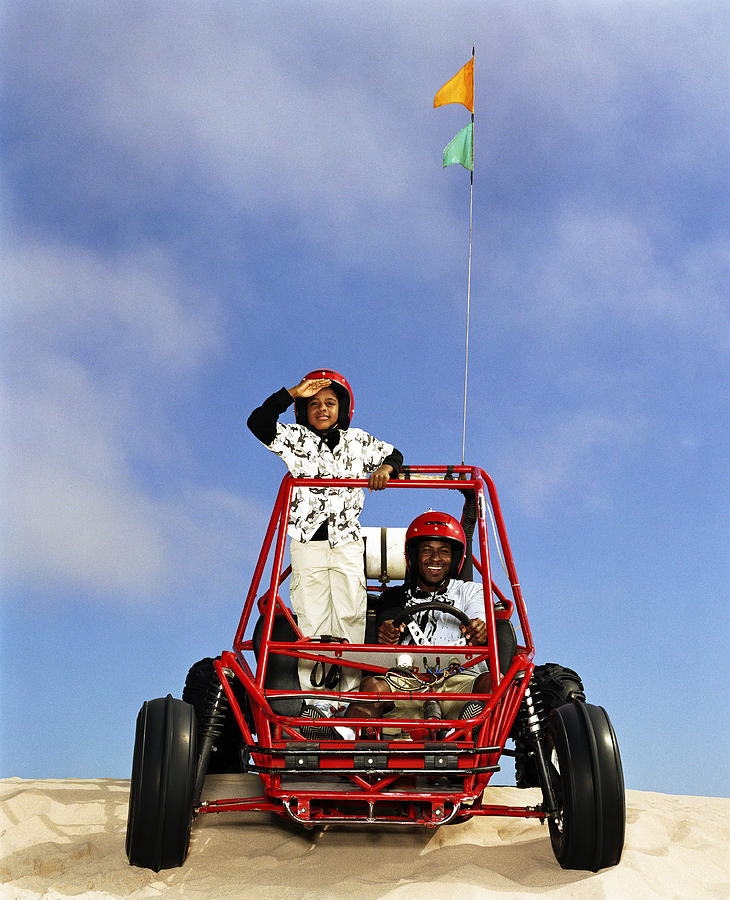 Father and son (8-10) riding in dune buggy Photograph by Ryan McVay