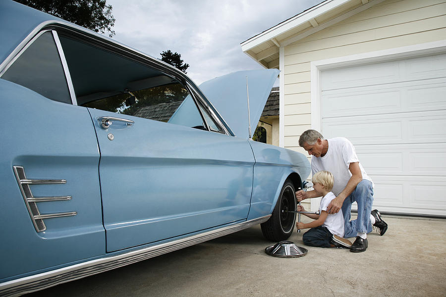 Father and son changing a tire Photograph by Skodonnell