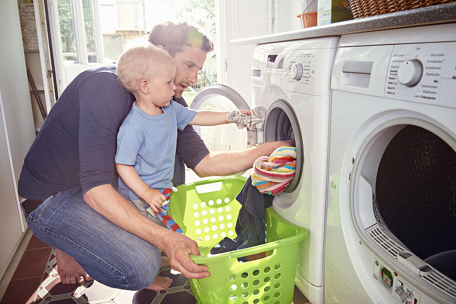 Father and son doing laundry together Photograph by Uwe Krejci