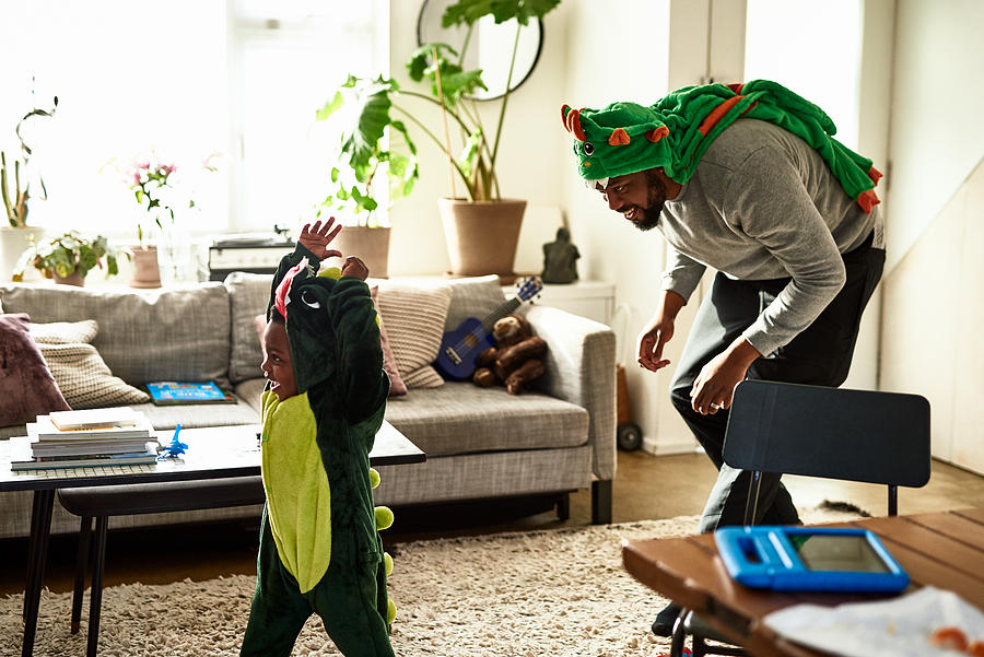 Father and son dressed as dragons playing in living room Photograph by 10000 Hours