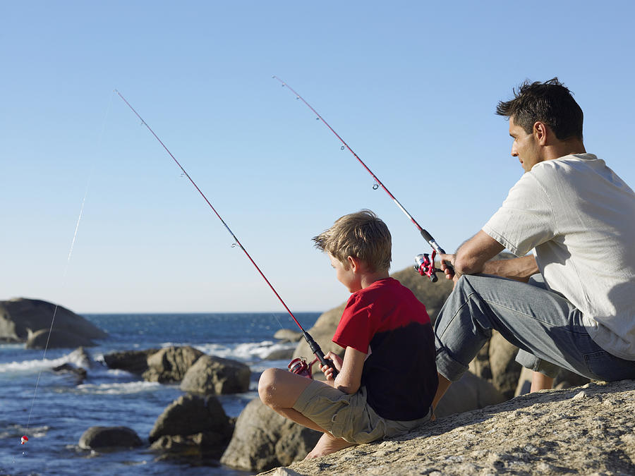 Father and Son Fishing on a Rock Photograph by Digital Vision.