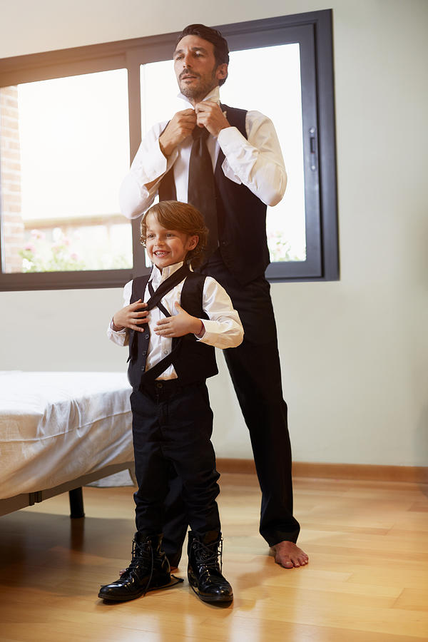 Father and son getting dressed Photograph by Morsa Images