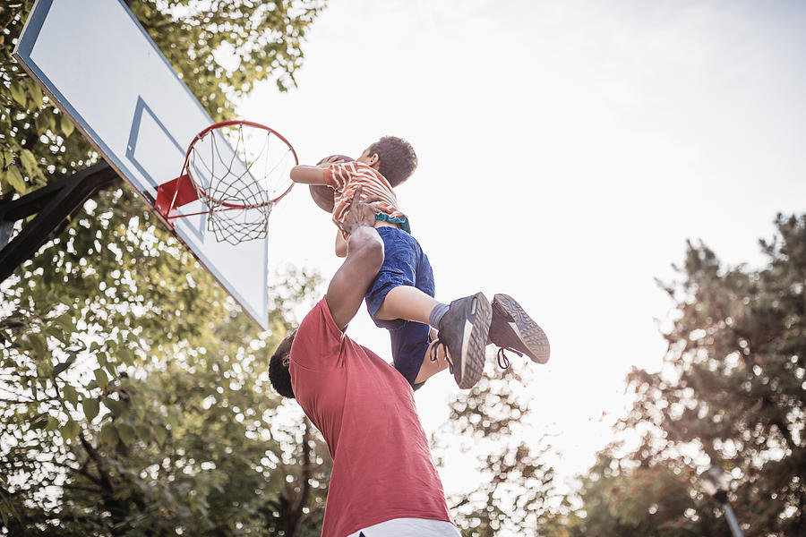 Father and son having fun, playing basketball outdoors Photograph by NoSystem images