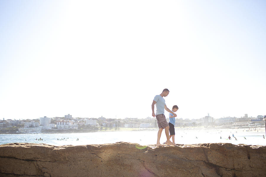 Father and son North Bondi walking on rocks Photograph by Wander Women Collective