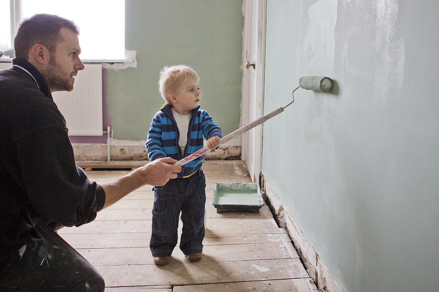 Father and son painting wall Photograph by Kate Mitchell
