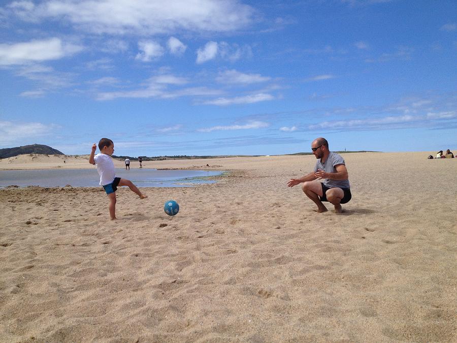 Father and son playing football on the beach Photograph by Amaia Arozena & Gotzon Iraola
