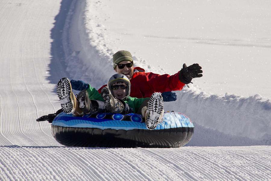 Father and son snow tubing on groomed path Photograph by David Epperson