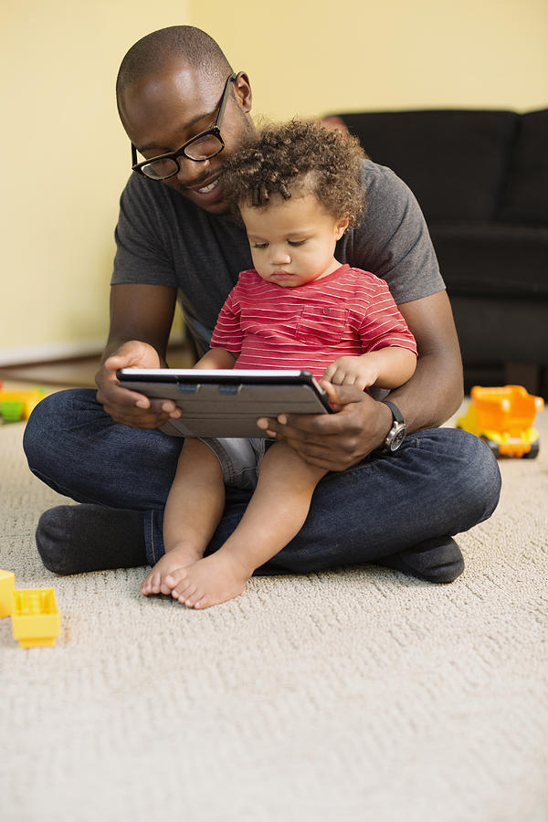 Father and toddler son using digital tablet Photograph by Roberto Westbrook