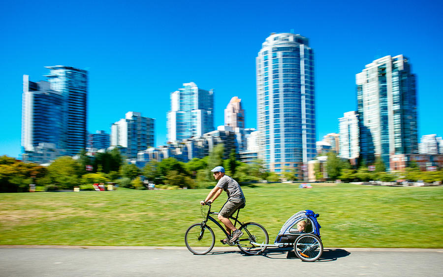 Father carries son in bicycle trailer in Vancouver Canada Photograph by Ferrantraite