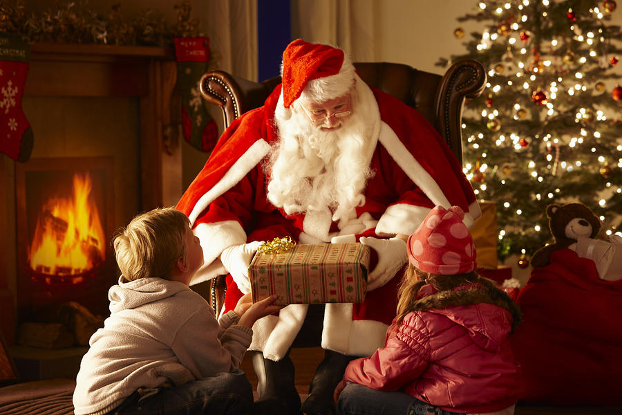 Father Christmas giving gift to children in grotto Photograph by Stocknroll