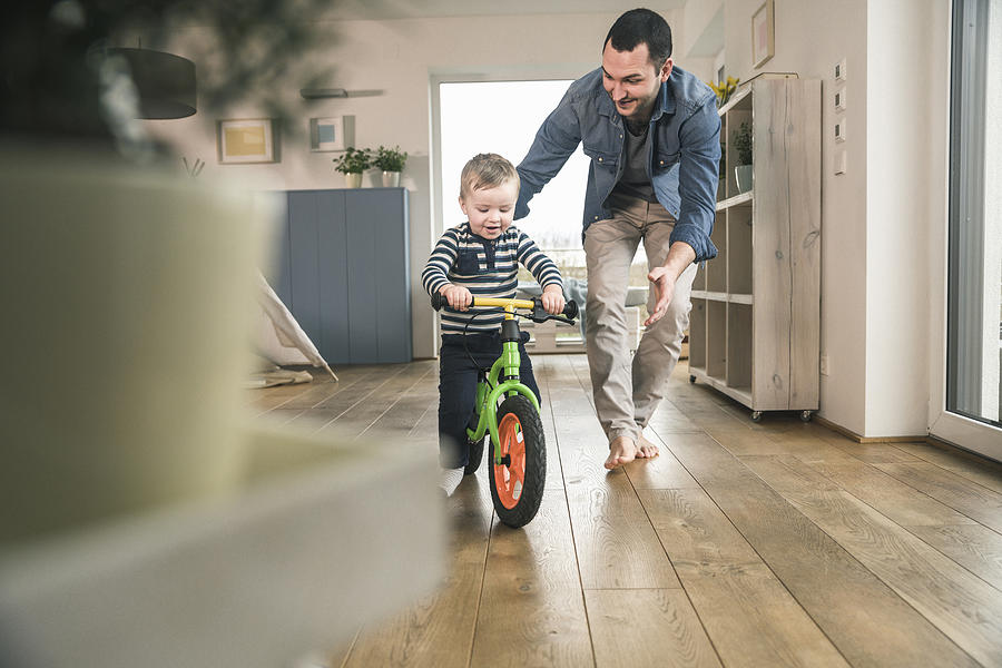 Father helping son riding with a balance bicycle at home Photograph by Westend61