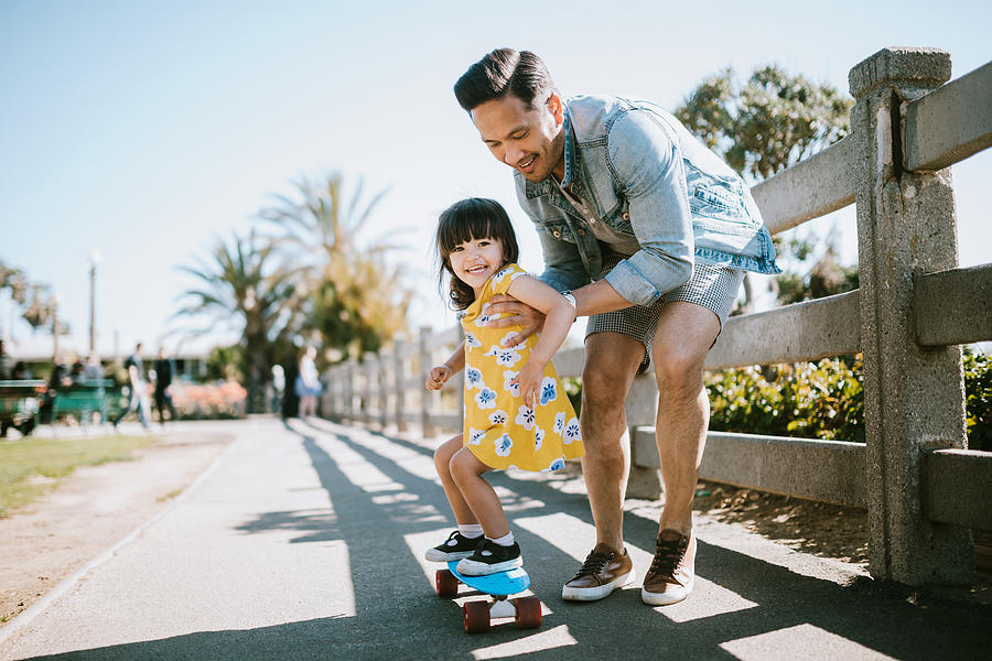 Father Helps Young Daughter Ride Skateboard Photograph by RyanJLane