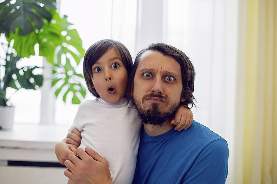 father in a blue T-shirt and a son in a white T-shirt are sitting on the windowsill large window Photograph