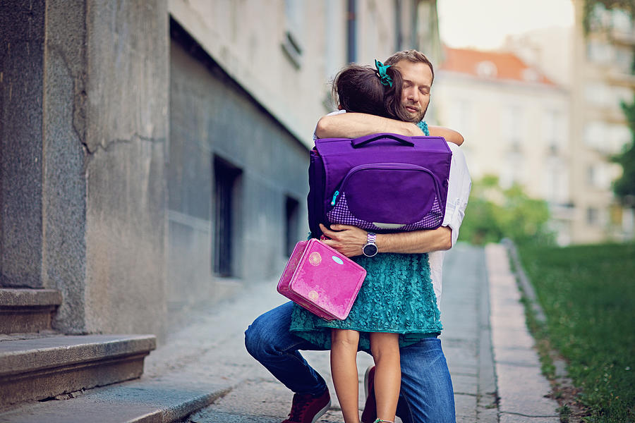 Father is sending his sad daughter to school for first time and trying to relax her Photograph by Praetorianphoto
