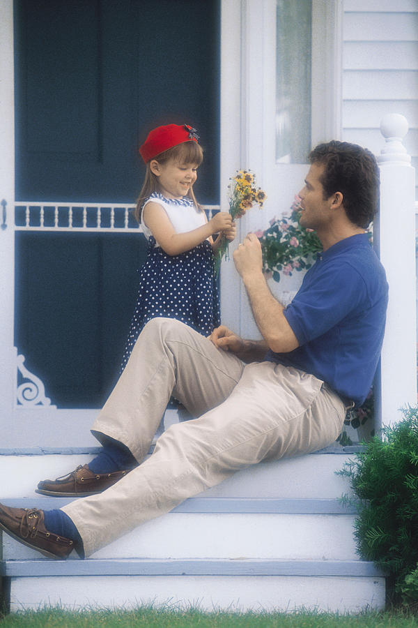 Father on porch receiving flowers from daughter Photograph by Comstock