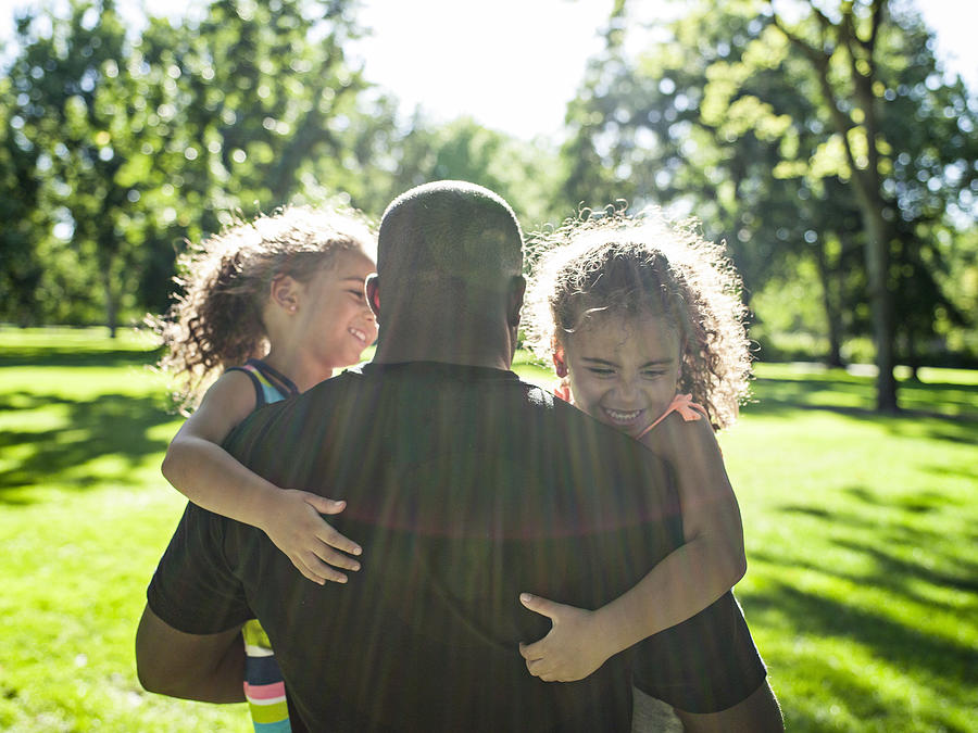 Father playing with twin daughters in park Photograph by Tony Anderson