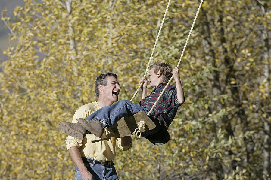 Father pushing his son on a swing Photograph by Comstock Images