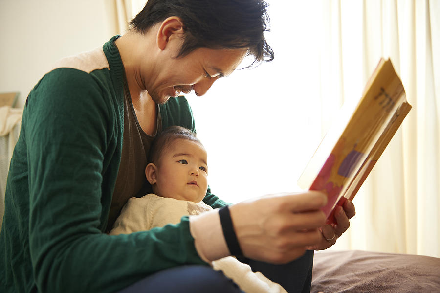 Father reading a picture book for his baby Photograph by Jaunty Junto