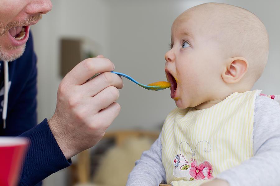 Father spoon feeding baby daughter Photograph by Christine Schneider