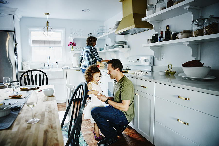 Father talking to young daughter in kitchen Photograph by Thomas Barwick
