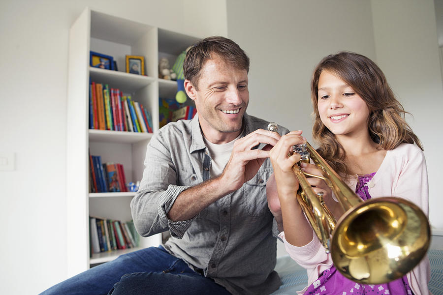 Father teaching daughter (8-9) how to play trumpet Photograph by Tomas Rodriguez