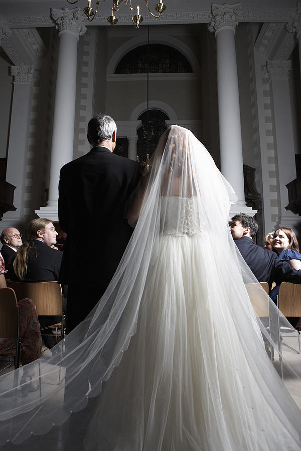 Father walking bride down church aisle, rear view Photograph by Michael Blann