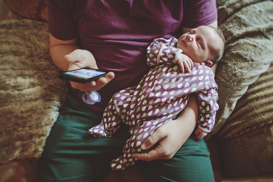 Father with his baby girl using a smart phone Photograph by Sally Anscombe