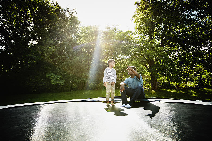 Father with young son on trampoline Photograph by Thomas Barwick