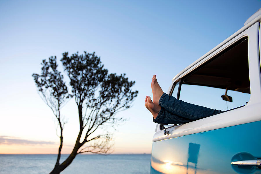 Feet out of camper van window at dusk Photograph by Martin Philbey