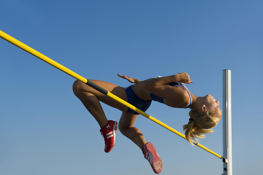 Female athlete jumping over the lath Photograph by Technotr