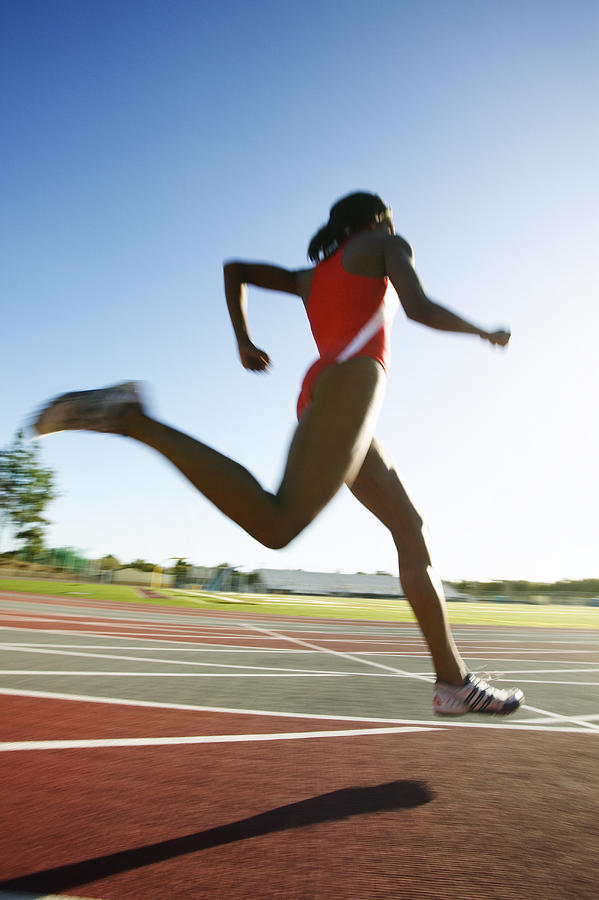 Female athlete running on track, low angle view Photograph by Peter Griffith