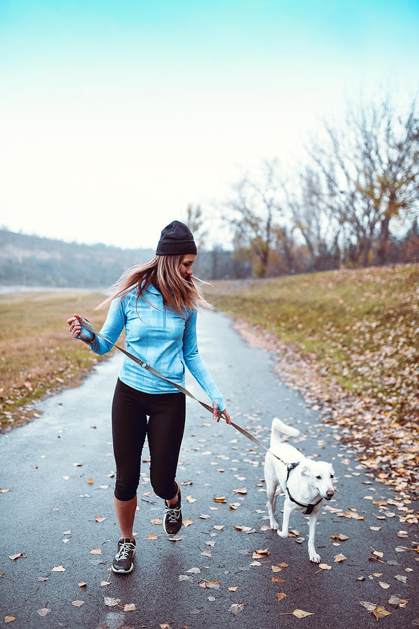 Female Athlete Running With Dog In Park Photograph by AleksandarGeorgiev