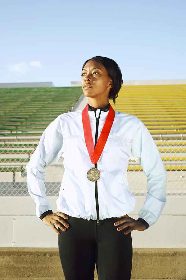 Female athlete wearing medal in stadium Photograph by Peter Griffith