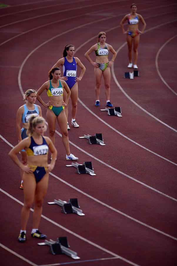 Female athletes standing behind starting blocks on track, elevated Photograph by Mike Powell