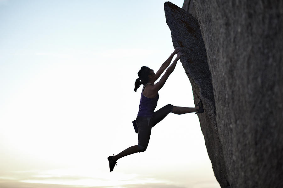 Female climber hanging in rock in the sunset Photograph by Klaus Vedfelt