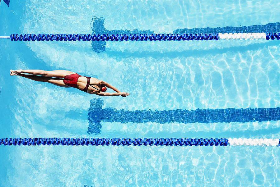 Female competitive swimmer diving into pool Photograph by Thomas Barwick