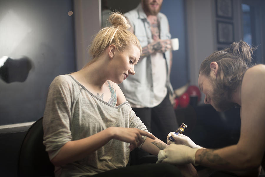 Female customer instructing artist in tattoo studio Photograph by Portra