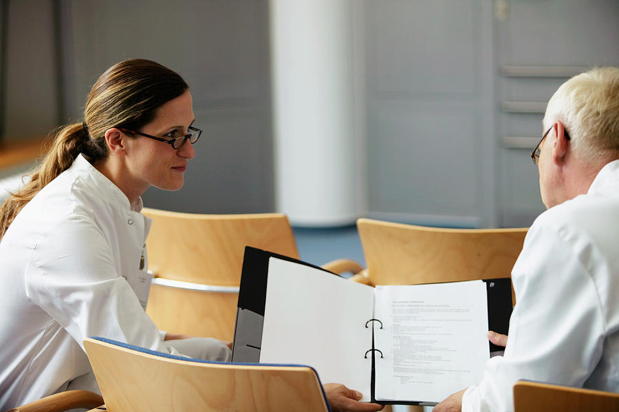 Female doctor showing notes to male colleague Photograph by Jochen Sand