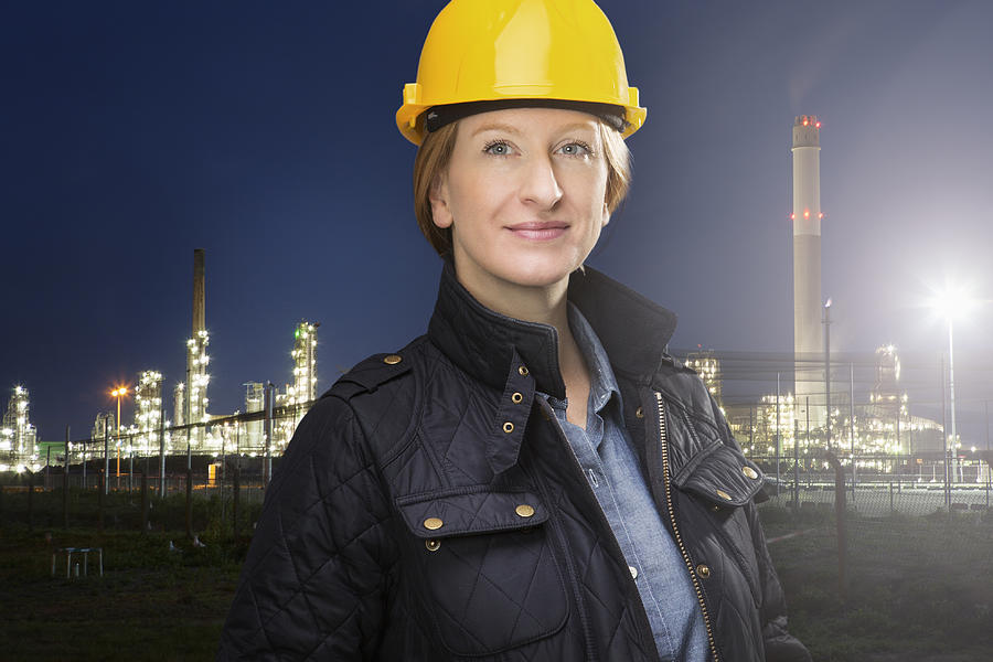 Female engineer stands in front of oil refinery. Photograph by Betsie Van Der Meer