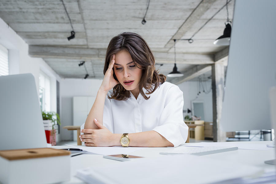 Female entrepreneur with headache sitting at desk Photograph by Izusek