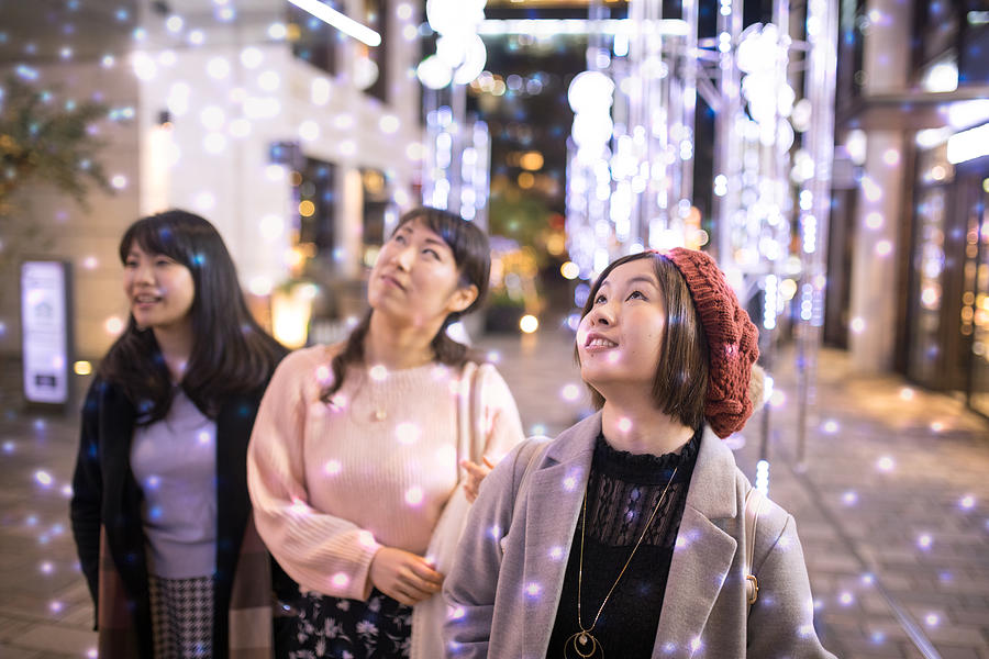 Female friends looking up in electrical snow white Christmas Photograph by Satoshi-K
