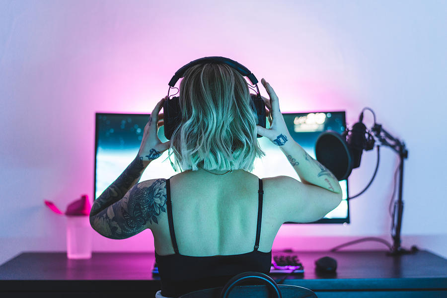 Female gamer putting her headphones on Photograph by Luza Studios